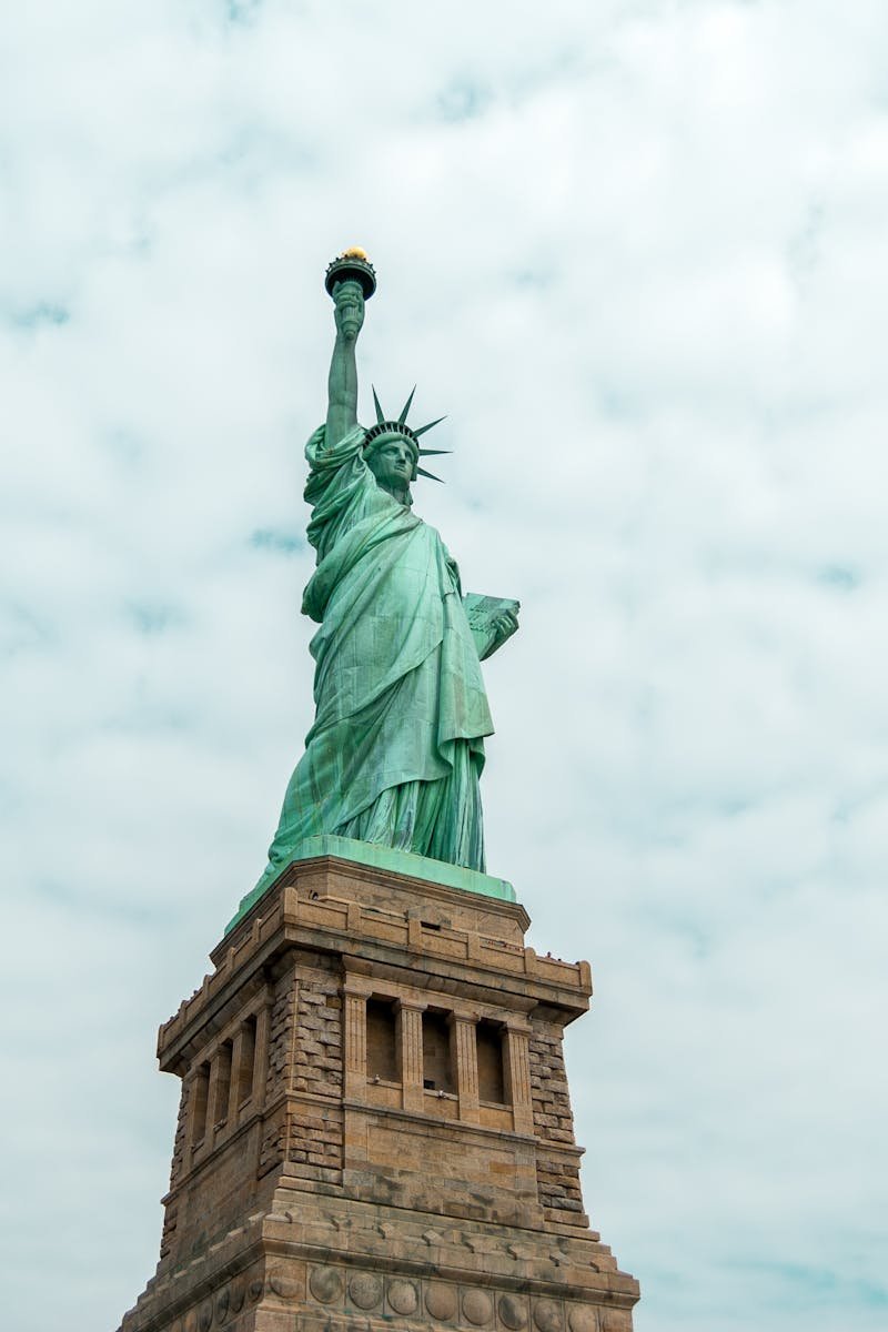 Iconic Statue of Liberty against a cloudy sky in New York City, symbolizing freedom.